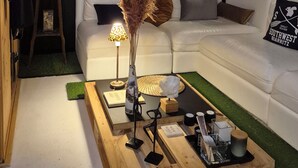 Un salon moderne avec un canapé blanc, une table basse sur laquelle sont disposés divers objets, et deux lampes.