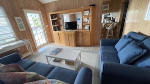 Ein Wohnzimmer mit einem blauen Sofa, einem weißen Couchtisch und einer Holzunterhaltungsecke mit Fernseher.