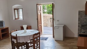 Una cucina compatta con zona pranzo, un piccolo frigorifero e una finestra che si affaccia su un giardino.