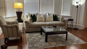 A living room with a beige sofa, a glass coffee table, a lamp, and a floor lamp.