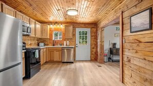 A wooden interior with a kitchen area, including a refrigerator, oven, and microwave. - Outdoor pvt pool! hot tub, deck, RIP Dolly! (Sevierville)