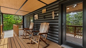 A log cabin with a wooden deck, rocking chairs, and a welcome sign. - Outdoor pvt pool! hot tub, deck, RIP Dolly! (Sevierville)