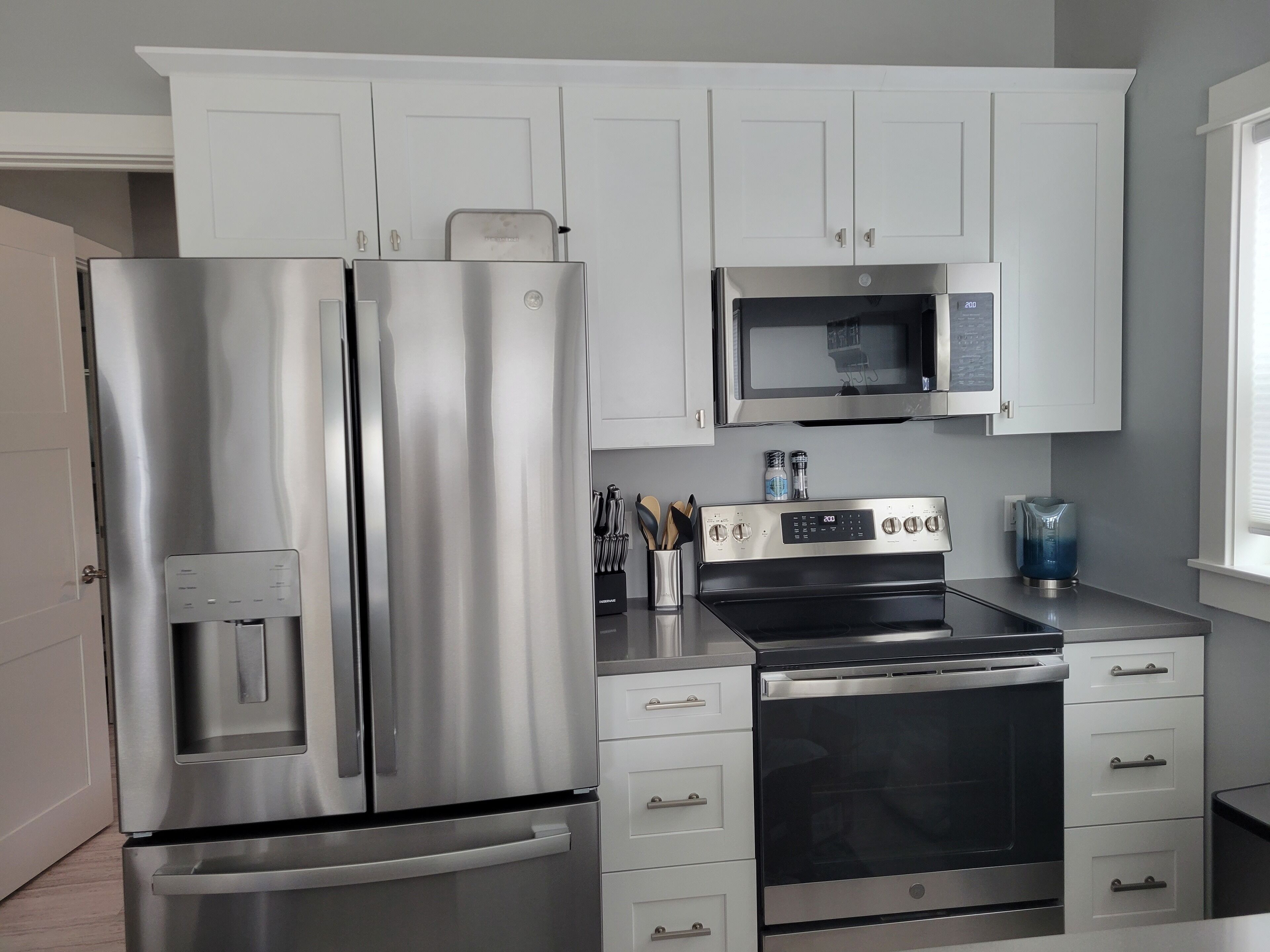 A modern kitchen with stainless steel appliances, white cabinets, and a microwave.