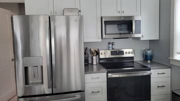 A modern kitchen with stainless steel appliances, white cabinets, and a microwave.