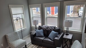 A modern living room with a leather sofa, patterned armchairs, and a striped rug. - Downtown Charlevoix, Riverwalk 107 (Charlevoix)