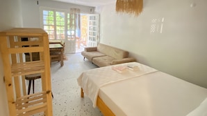 Een slaapkamer met een bed, een houten trap, een bank en een raam met uitzicht op het omliggende landschap.
