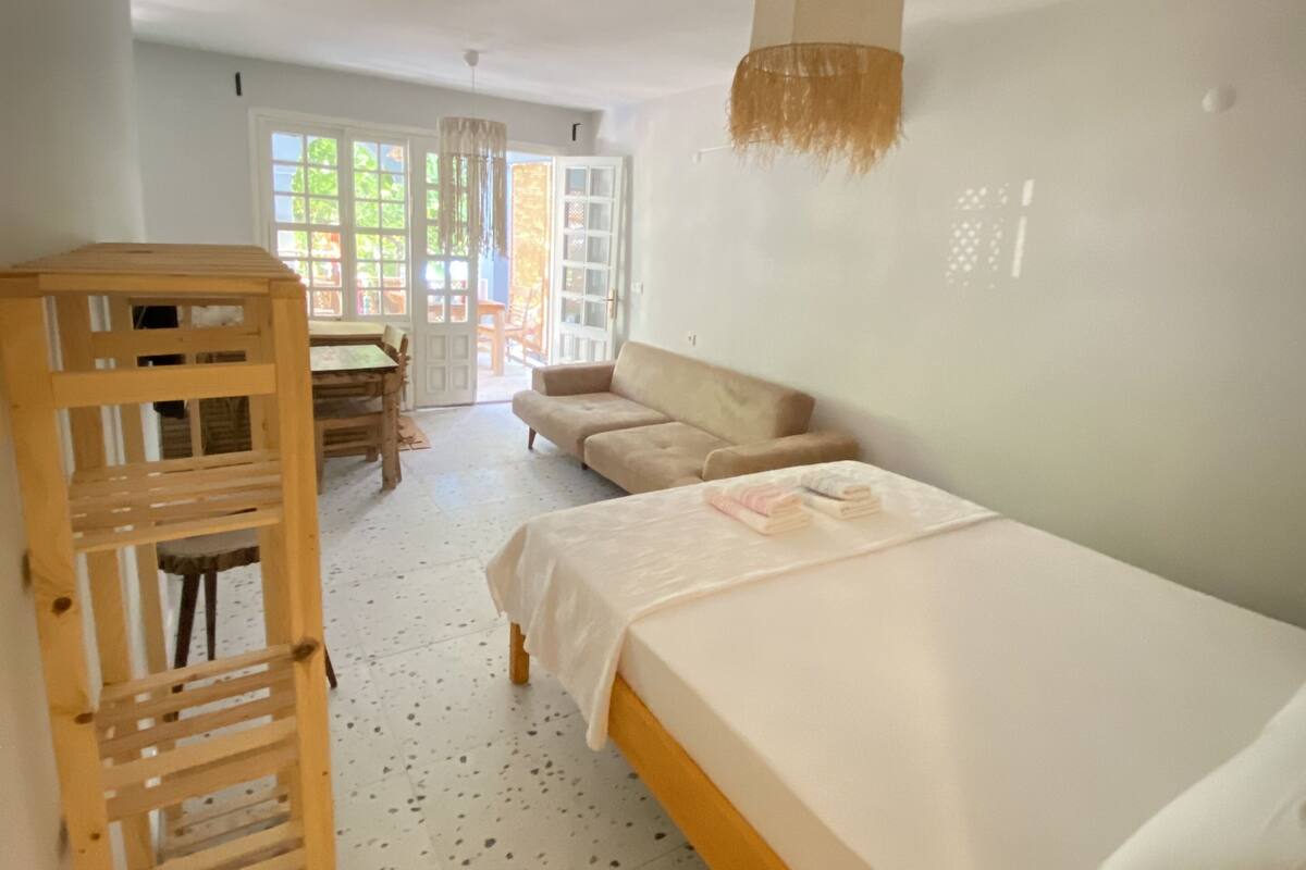 Une chambre à coucher avec un lit, une échelle en bois, un canapé et une fenêtre donnant sur l’extérieur.