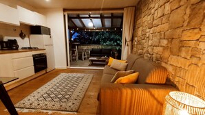 A modern living room with a sofa, a patterned rug, and a stone wall. - A little corner of paradise (Les Trois-Îlets)