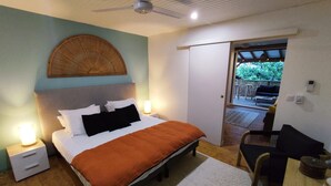 A bedroom with a bed, bedside lamps, a ceiling fan, and a view of an outdoor patio area. - A little corner of paradise (Les Trois-Îlets)