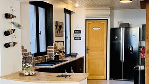 Een keuken met een houten aanrecht, een spoelbak, een koelkast en een deur met de tekst 'TOILETRIES'.