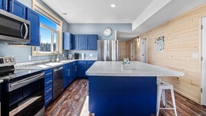 Una cocina moderna con armarios azules, electrodomésticos de acero inoxidable y una isla grande.