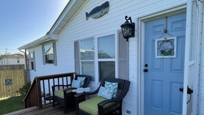 A white house with a blue door, a porch with wicker furniture, and a welcome sign. - 5 minute walk to beach - come relax, enjoy family time and even fish. (Port St. Joe)