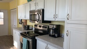 A kitchen with white cabinets, a stainless steel stove, a microwave, and a coffee maker.