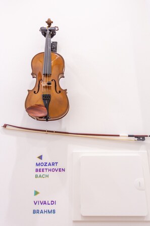 A violin on a wall with a bow, and a music stand with labels 'MOZART BEETHOVEN BACH' and 'VIVALDI BRAHMS'. - BAIRRO ALTO MUSIC GUEST HOUSE STRAUSS (Lisboa ciudad)