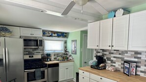 Een moderne keuken met witte kasten, roestvrijstalen apparatuur en een houten eettafel.