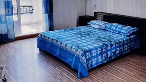 Un dormitorio con cama, ventana con cortinas, piso de madera y un equipo de aire acondicionado en la pared.