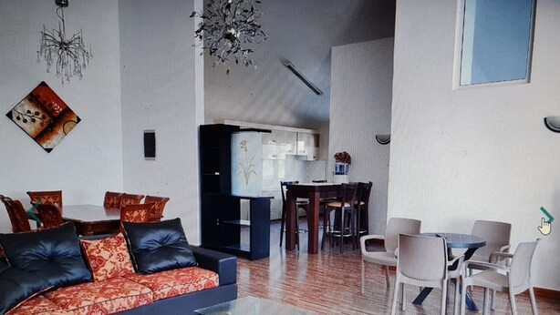 Una sala de estar moderna con un sofá modular, una mesa de centro de vidrio y un comedor con una mesa y sillas.