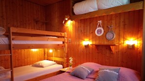 Ein gemütliches Blockhausszimmer mit zwei Etagenbetten, einer Holzwand und einem Regal mit Handtüchern.