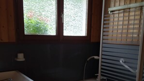Ein Badezimmer mit Waschbecken, Badewanne und einem Fenster mit Jalousien.