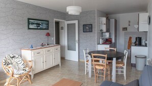 Une cuisine moderne avec des meubles blancs, une table à manger et une chaise en osier.