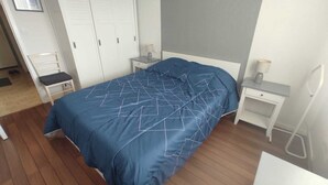 Une chambre à coucher comprenant un lit, deux tables de chevet, une chaise et une armoire.