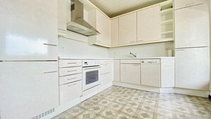A kitchen with white cabinets, a built-in oven, a sink, and a dishwasher. - Apartment Huningue (Huningue)