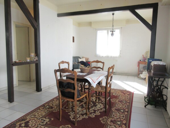 A dining area with a table set for four, surrounded by wooden chairs, a patterned rug, and a window with natural light.