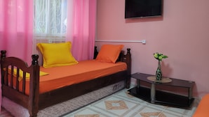 A bedroom with a bed, a TV mounted on the wall, and a small table with a vase.