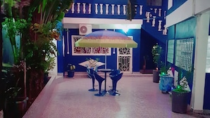 A courtyard with a patterned floor, a table with chairs, and a decorative umbrella.