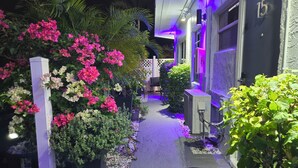A narrow pathway flanked by vibrant flowers and greenery, leading to a building with a number '15' sign. - Barefoot Mailman Inn & Suites (Lantana)