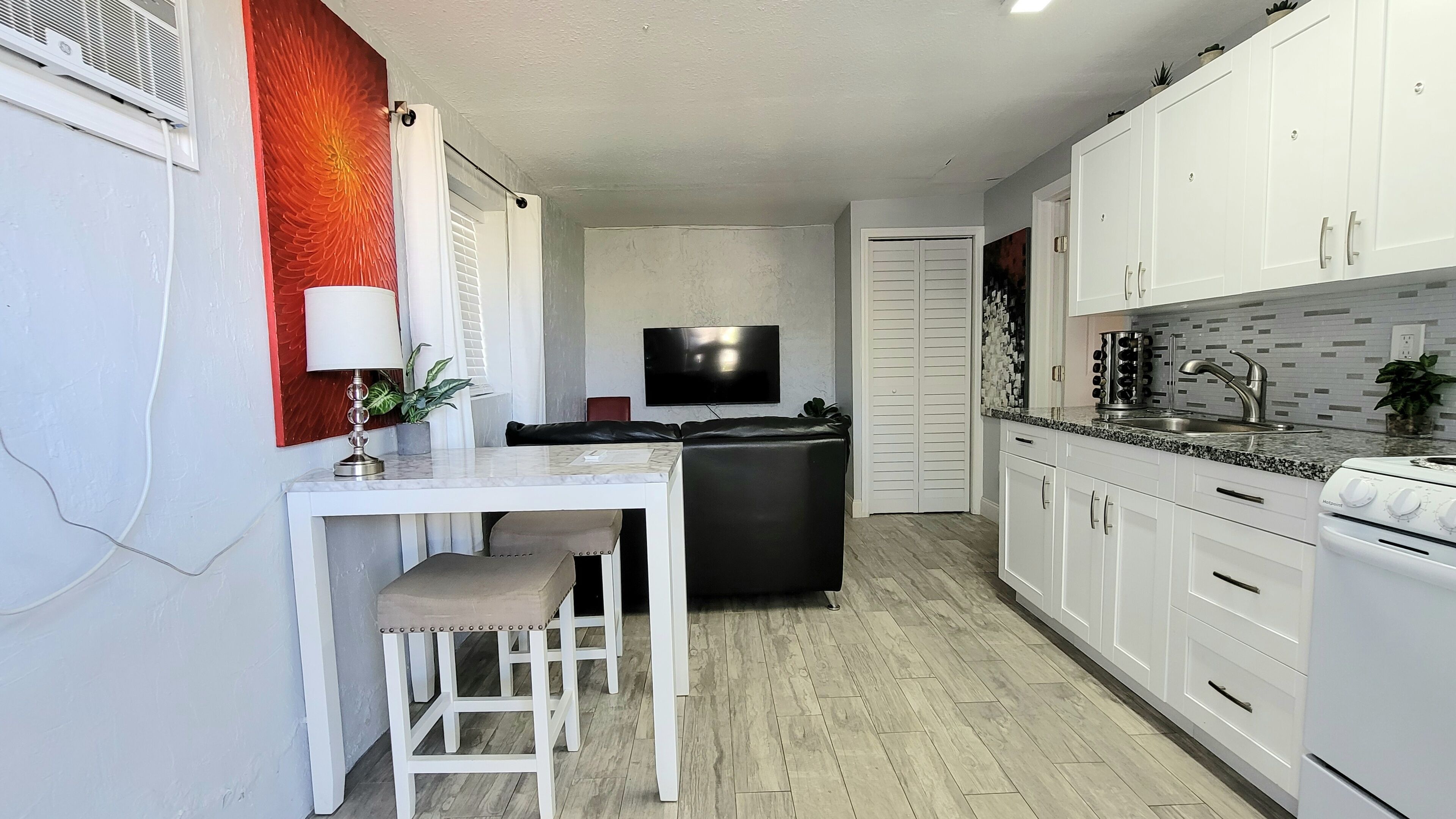 A compact kitchen with white cabinets, a black countertop, and a built-in oven.