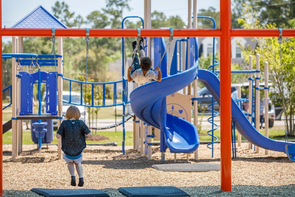 A playground with a blue slide, a swing set, and a climbing structure.