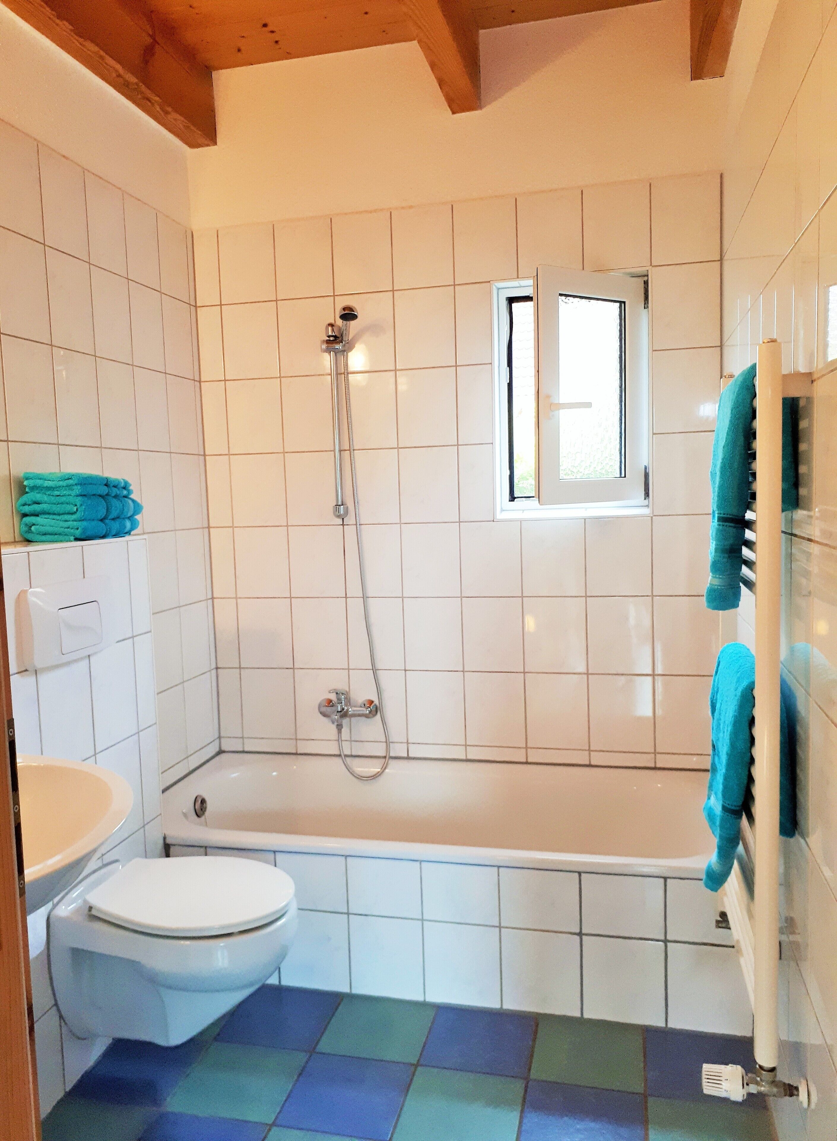 A bathroom with a bathtub, toilet, and a window.