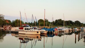 A marina with several boats docked in calm water, surrounded by trees and a clear sky.