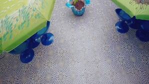 Habitació amb un paviment de disseny blau i verd, una petita planta en test i una taula amb caires blaus.