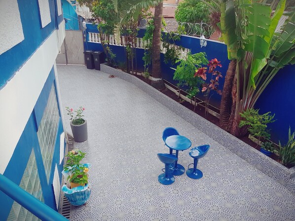 A small outdoor area with a blue table and chairs, surrounded by potted plants and a blue wall. - Magnificent studio near the beach (Nosy Be)
