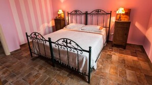 A single bed with a metal frame, two bedside tables with lamps, and a pink-striped wall.