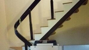 A staircase with a black handrail and white steps, leading to a landing area with a white object.