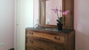 A wooden dresser with a mirror, drawers, and a small plant on top.