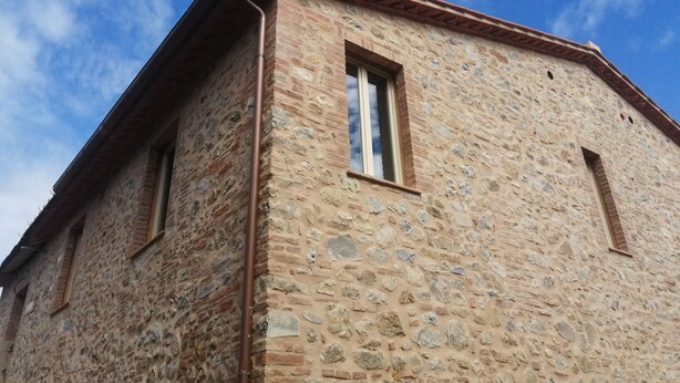 A stone building with a visible window and a metal gutter.