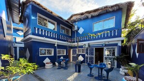 A courtyard with a blue building, outdoor seating, and potted plants.
