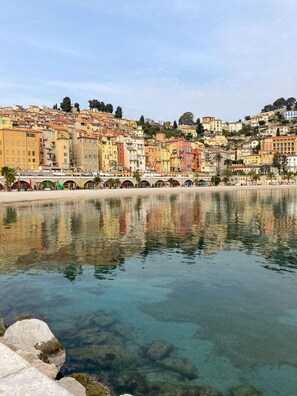 A coastal town with colorful buildings, a clear waterfront, and a stone bridge. - Apartment 100 meters from the beach (Menton)
