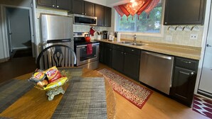 A modern kitchen with dark cabinets, stainless steel appliances, and a window with decorative curtains. - Fireside Ranch of Romeo (bruce twp)