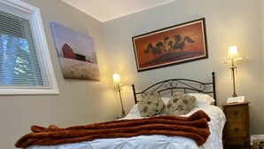 A neatly made bed with a white duvet and a brown blanket, flanked by two lamps and a nightstand with a lamp. - Fireside Ranch of Romeo (bruce twp)