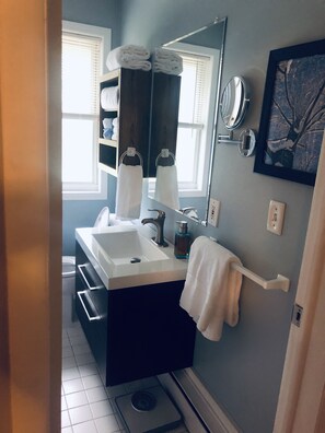 A bathroom with a white sink, a mirror, a towel rack, and a scale.