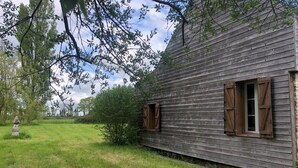 Una cabaña de madera rústica con un hito de piedra al frente, rodeada de vegetación exuberante.
