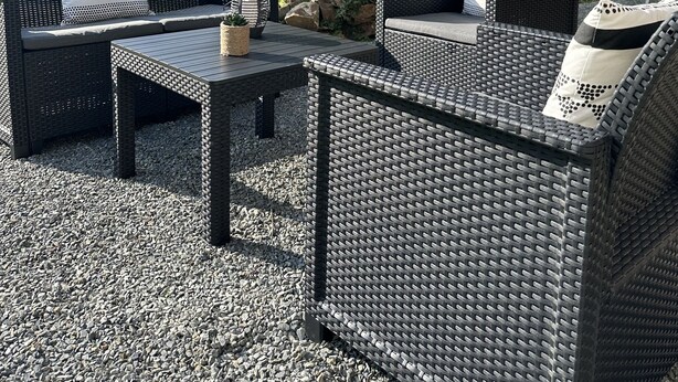 Un área de estar al aire libre con mobiliario de mimbre y una pérgola.