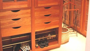 Ein hölzerner Kleiderschrank mit mehreren Einlegeböden, Schubladen, einer Kleiderstange und einem Schuhregal.