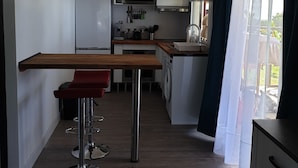 Eine kompakte Küche mit Kochinsel, Kühlschrank, Mikrowelle und Waschmaschine.