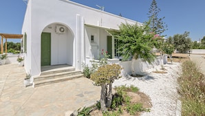 Un bâtiment blanc avec une porte verte et un petit porche.